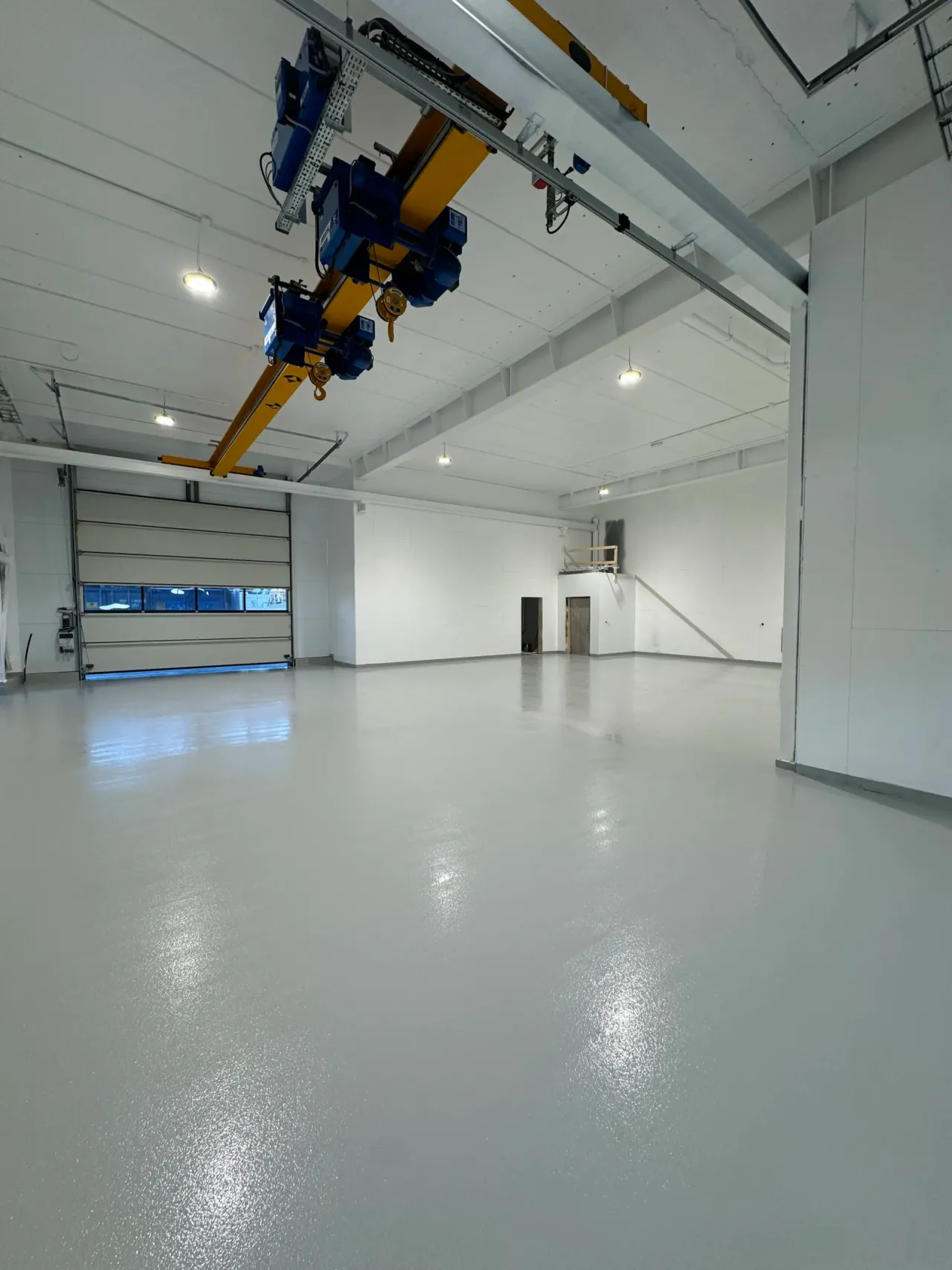 Lyst, blankt gulv i en industrihall med traverskran