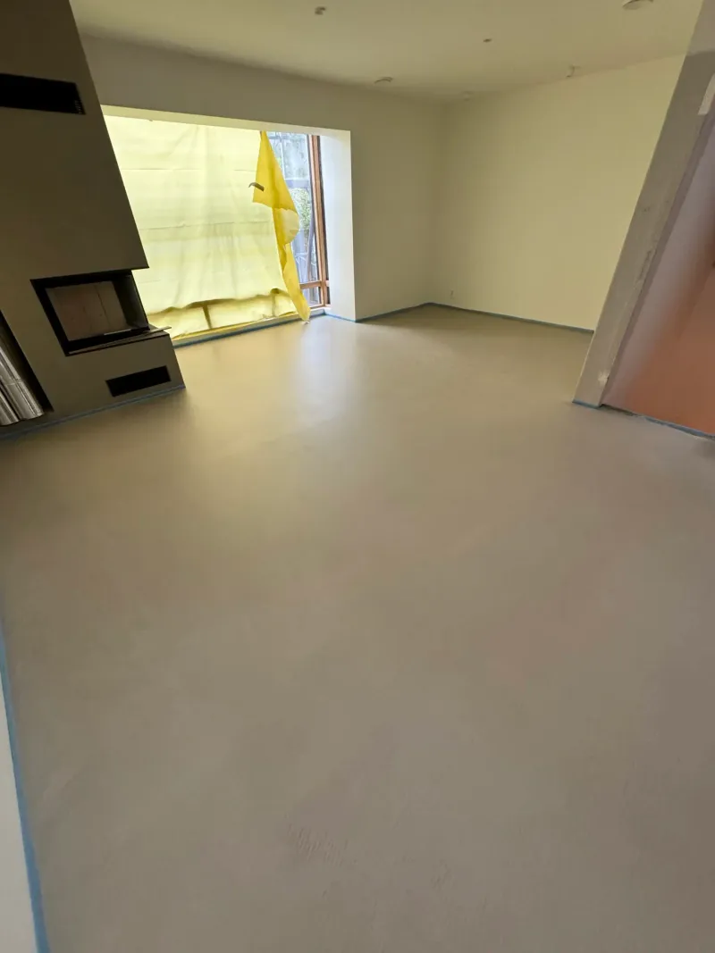 Ferdig avrettet gulv i et nybygd rom med store vinduer