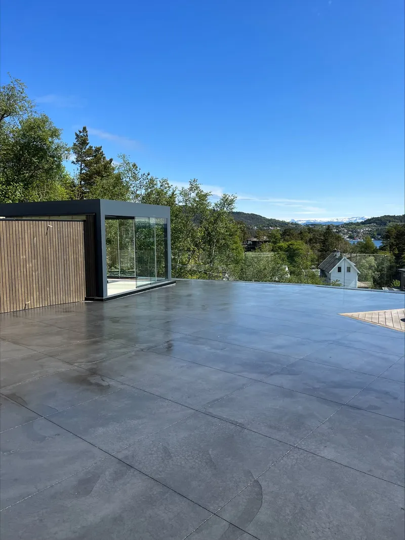 Ny støpt betongflate på en takterrasse med glassrekkverk