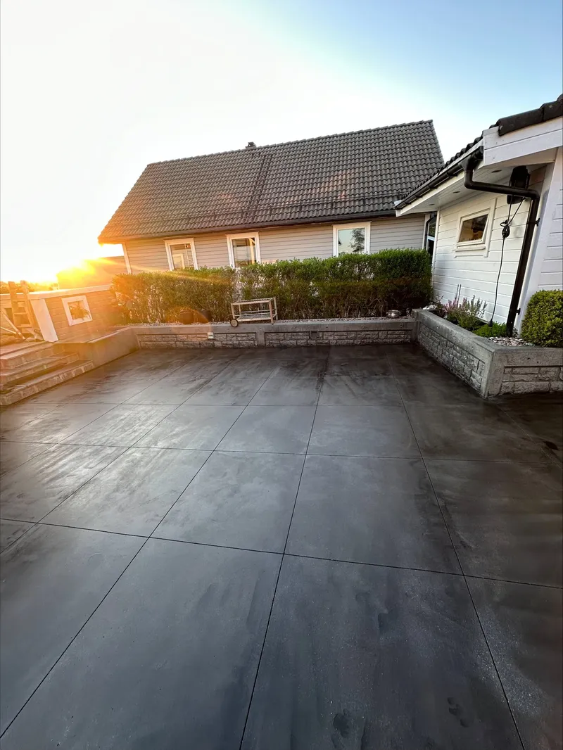 Ny støpt betongflate på en uteplass ved et hus