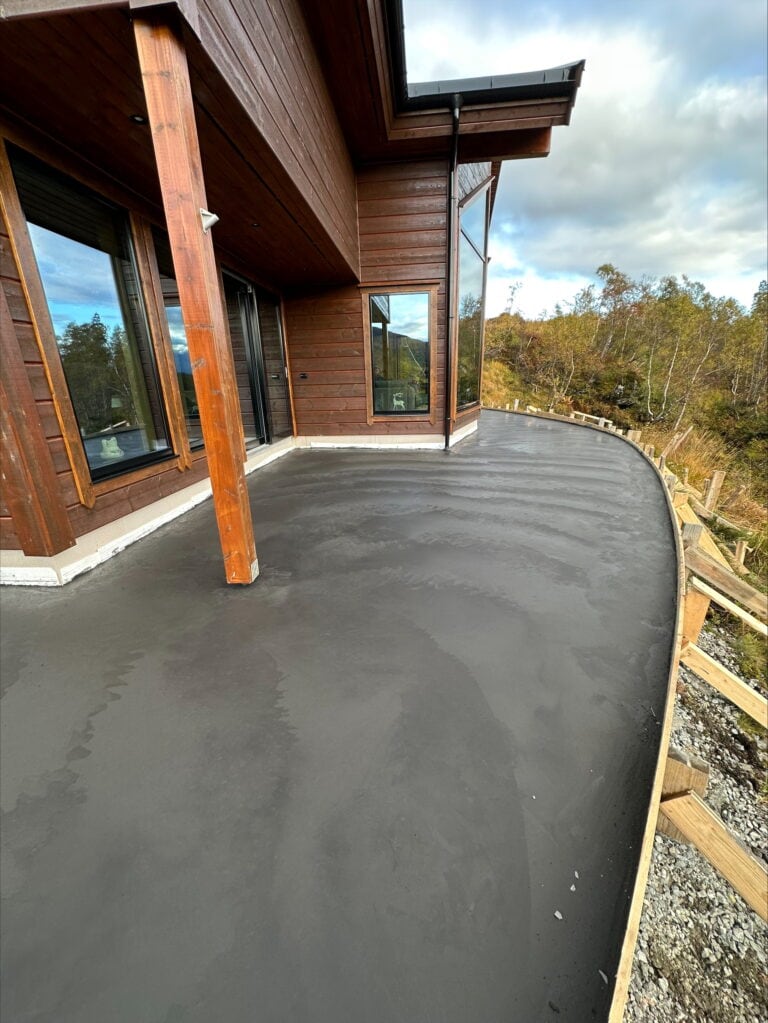 Ny støpt betongterrasse på tak med utsikt over skog og himmel.