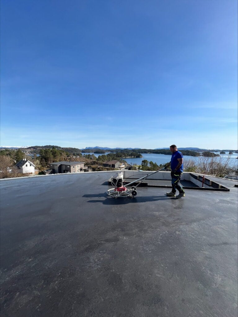 Arbeid med betong å ny betongflate med utsikt over sjø og landskap.