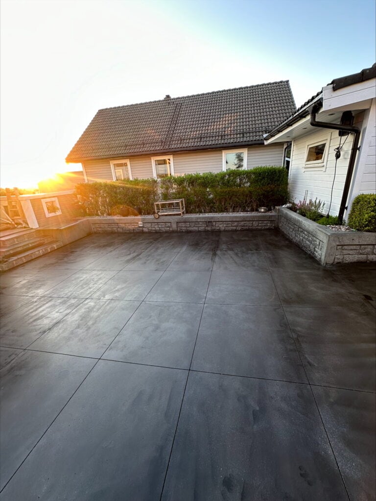 Takterrasse med ny støpt betongflate, hus og hage i bakgrunnen.