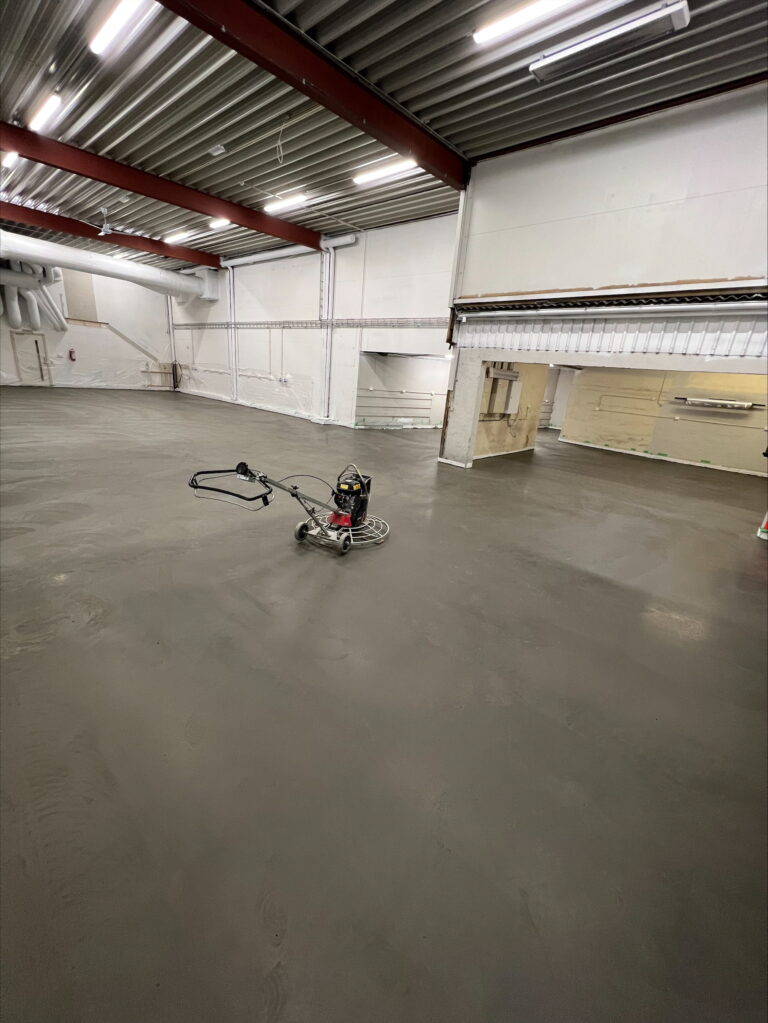 Gulvstøp og avretting i et stort industrilokale med ny betongoverflate.